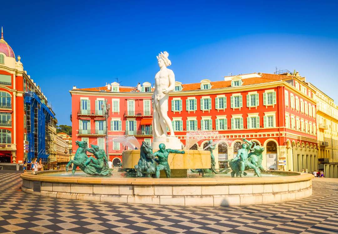 Fontana del Sole con statua di Apollo e palazzi rossi in stile sabaudo a Place Massena, Nizza