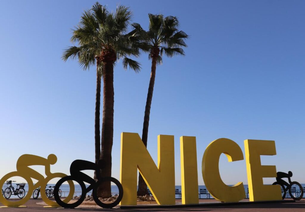 Scritta monumentale NICE gialla con palme e biciclette, Promenade des Anglais, Nizza